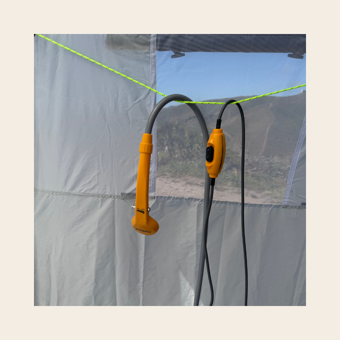 pommeau de la douche nomade 12V et son bouton de mise en fonction installés dans une cabine de douche